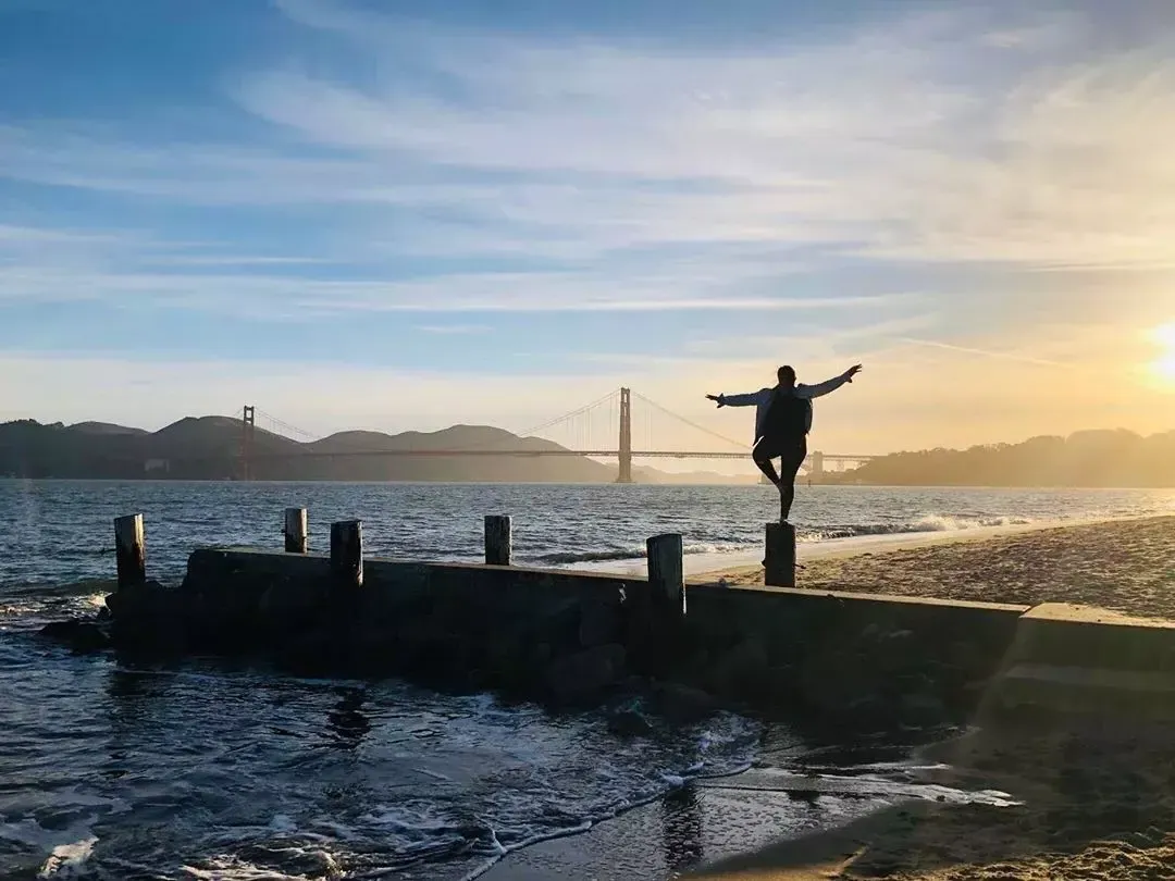 A woman stands on A pier in San Francisco's Marina neighborhood, looking out at the Golden Gate桥.